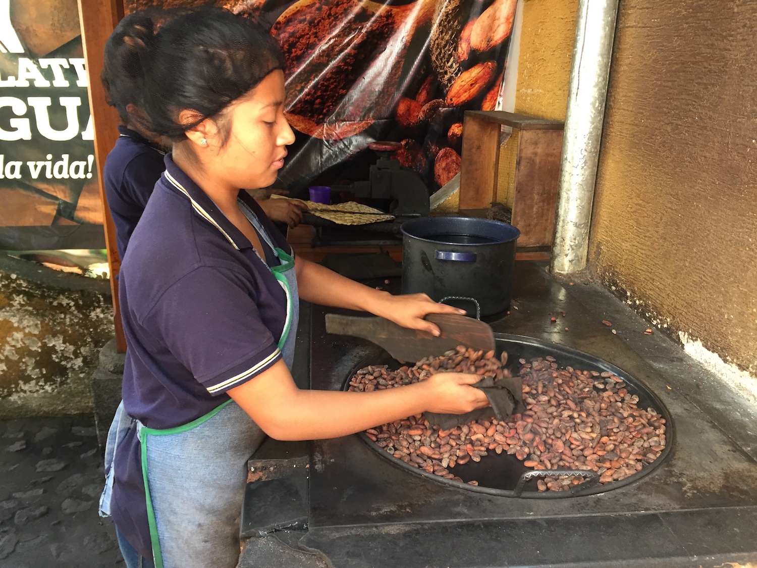 Mayan woman roasting cacao beans over wood-fi red grill, creating an enticing aroma.